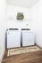 Modern laundry room with sleek washing machine and dryer, featuring stylish storage baskets and elegant wooden flooring.