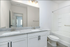 Modern bathroom with dual sinks, elegant granite countertop, and spacious bathtub offering a luxurious experience.