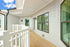 Charming apartment balcony with sleek white railings, spacious wooden flooring, and large, bright windows.