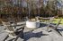 Inviting outdoor patio with modern fire pit, surrounded by comfortable chairs and a hammock, set against a serene wooded backdrop.