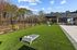 Inviting communal outdoor space featuring lush green lawn, cornhole games, and patio seating under a pergola, ideal for relaxation and entertainment.