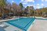 Inviting outdoor pool area surrounded by lush trees, featuring stylish lounge chairs and cozy cabanas.