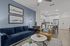 Chic open-concept living area featuring a modern kitchen, cozy blue velvet sofa, stylish artwork, and wooden floors.