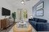 Chic living room featuring a modern blue sofa, elegant wooden console, and a peaceful view through large windows.