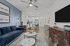 Modern living space featuring a cozy blue sofa, sleek marble coffee tables, and a stylish open-concept kitchen.
