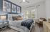 Chic bedroom with a plush bed, modern artwork, and soft natural lighting creating a serene ambiance.