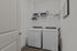 Modern laundry room featuring high-efficiency washer and dryer, sleek shelving with storage boxes, and stylish white decor.
