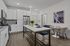 Chic modern kitchen with white cabinetry and stainless steel appliances, featuring a stylish island with seating and a cozy dining nook.