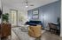 Chic, modern living room with stylish decor, featuring a blue sofa, trendy chairs, and a cozy working space next to large windows with natural light.