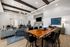 Modern living area featuring a natural wood table, plush seating, and industrial lighting in a stylish open-concept design.