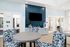 Modern and inviting community lounge featuring stylish geometric chairs, a sleek round table, and a large entertainment wall with elegant decor.