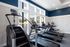 Modern fitness center with sleek treadmills and a stair stepper, flooded with natural light from large windows.