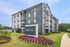 Modern Novo Blue Ridge building with stylish facade, lush landscaping, and vibrant flowerbeds under a clear sky.