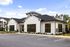 Charming single-story building with modern architecture, complemented by large windows and well-maintained landscaping under a bright blue sky.