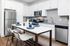 Modern kitchen with sleek white cabinets, stainless steel appliances, and a chic dining area with stylish barstools.