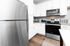 Modern kitchen with sleek stainless steel appliances, elegant white cabinetry, and polished dark wood flooring.