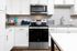 Modern kitchen with sleek stainless steel appliances and stylish white cabinets, featuring elegant countertops and subway tile backsplash.
