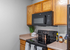 Modern kitchen with sleek black appliances, wood cabinets, and stylish decor accents.