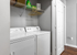 Modern in-unit laundry room with sleek washer and dryer, featuring convenient shelving for storage and organization.