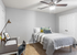 Bright and inviting bedroom with plush bedding, stylish desk area, modern ceiling fan, and ample closet space for a cozy and functional living experience.