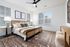 Inviting bedroom with stylish decor, featuring a cozy bed with plush pillows, large windows for natural light, and elegant wall art.