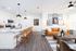 Contemporary open-plan living area with sleek kitchen, stylish pendant lighting, and cozy seating, perfect for modern living.