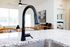 Sleek kitchen with modern black faucet on granite countertop, bright open-concept living space in the background.