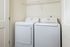 Modern laundry area featuring a sleek washer and dryer set with convenient shelving above.