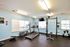 Bright and inviting fitness room featuring modern gym equipment including a treadmill, elliptical, and weightlifting station.