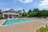 Inviting outdoor pool area with comfortable lounge chairs, surrounded by lush greenery and a charming clubhouse backdrop.