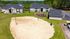Charming apartment complex surrounded by lush greenery, featuring a sandy volleyball court and a children's playground, perfect for an active lifestyle.