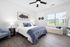 Bright and inviting bedroom with modern decor, featuring a cozy bed, elegant artwork, and large window offering natural light.