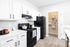 Sleek modern kitchen with white cabinetry, black appliances, and spacious pantry complemented by stylish countertops.