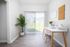 Bright and modern home office with sleek white desk, stylish decor, and large window offering a serene garden view.