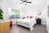 Bright bedroom with a cozy bed, elegant mirrors, and a view of lush greenery through large windows.
