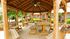 Charming wooden gazebo with benches and tables surrounded by lush greenery, perfect for outdoor gatherings.