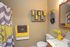 Charming bathroom with creative yellow and gray accents, featuring a stylish shower curtain, wall-mounted jars, and a bright decorative board.