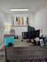 Modern home office with a sleek wooden desk, vibrant abstract artwork, and ambient lighting, ideal for productivity and creativity.