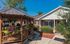 Charming courtyard view of a quaint brick home featuring a delightful wooden gazebo and lush greenery in a serene setting.