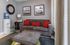 Chic and cozy living space showcasing a plush gray sofa with vibrant red cushions, complemented by contemporary abstract art and a stylish water dispenser.