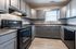 Modern kitchen with sleek gray cabinetry, black appliances, and a sunlit window offering ample natural light.
