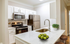 Modern kitchen with sleek stainless steel appliances, elegant white cabinetry, and a stylish breakfast bar with chic decor.