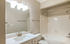 Modern bathroom with elegant vanity, bright lighting, and a pristine bathtub for a relaxing experience.