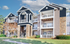 Elegant apartment complex showcasing charming stone accents, spacious balconies, and lush greenery under a bright blue sky.