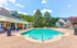 Inviting outdoor pool area surrounded by lush greenery and elegant brick architecture, perfect for relaxation and leisure.
