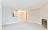 Bright and inviting living space with plush carpeting, modern recessed lighting, a cozy fireplace, and an open kitchen layout.