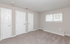 Bright, spacious bedroom with cozy carpet, three-panel doors, and large window for natural light.