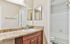 Elegant bathroom featuring a granite countertop with a modern sink, wooden cabinetry, and a bright, inviting tiled shower area.