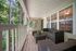 Charming covered patio with wicker seating, overlooking a lush, wooded area for tranquil outdoor relaxation.