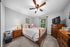 Inviting bedroom with elegant wooden furniture, cozy bed, and large window overlooking lush greenery.